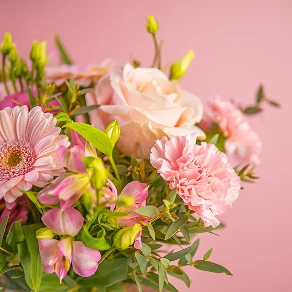 someone holding yellow and peach flowers